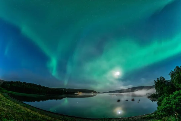 Aurora borealis, dolunaylı kuzey yeşil ışıklar ve göl üzerindeki gece gökyüzünde yıldızlar, suda yansıyan yansıma, gece sisi. Joesjo, Lappland, İsveç
