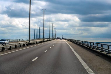 Danimarka ve İsveç arasında denizi kapsayan Öresund Köprüsü, araçlı yol, bulutlu gökyüzü ve uzun modern mühendislik bağlantısı. Öresund, Danimarka 12 Temmuz 2025
