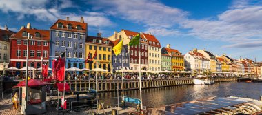 Kopenhag 'daki Nyhavn Kanalı' nda renkli tarihi rıhtım binaları, açık hava kafeleri ve limanın yanındaki güneşli mavi gökyüzünün altında restoranlar var. Kopenhag, Danimarka 13 Temmuz 2025