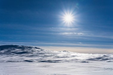 Laponya 'nın uçsuz bucaksız karlı havası berrak mavi bir gökyüzü altında uzanır. Güneş, donmuş platolar ve uzak dağlar boyunca parlak ışınlar saçarak el değmemiş, uzak Arktik çöllerini aydınlatır.