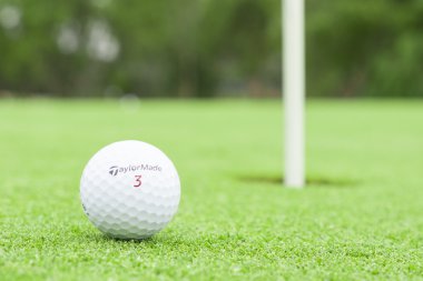 Melbourne, Avustralya - 18 Ocak 2014: A golf topu bir yeşil arka plan delik markalı Taylormade