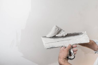 Beyaz macunu spatulaya koyan bir işçinin yakın çekimi..