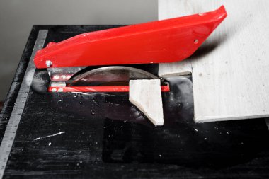 Elektrikli fayans kesiciyle fayanslar kesiliyor. İşçi eli seramik fayansları su kesme makinesiyle kesiyor.