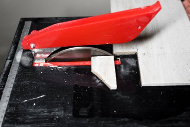 Elektrikli fayans kesiciyle fayanslar kesiliyor. İşçi eli seramik fayansları su kesme makinesiyle kesiyor.