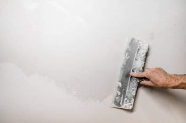 İşçi elleri spatula kullanır ve eski beton duvarı macunla sıkarlar. - Yakın çekim. Öncesi ve sonrası.