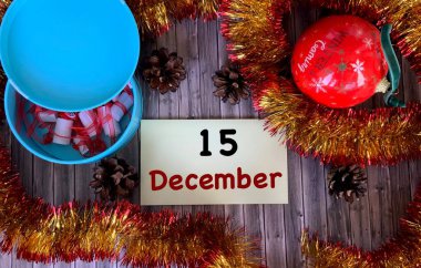 15 Aralık 'ta sarı bir çıkartmada. Noel balonu, tahta bir arka planda köknar konileri. Kışın ilk ayında. Aralık ayı takvimi..