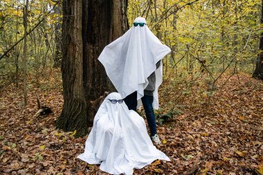 Ormanda hayalet meydan okuması. Beyaz çarşaflı ve güneş gözlüklü hayalet kılığına girmiş iki tanınmamış genç..