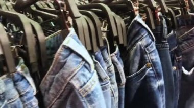  Askılarda çok sayıda kot pantolon bulunan bir sıra boyunca kamera hareketi. Alışveriş konsepti, Kara Cuma 