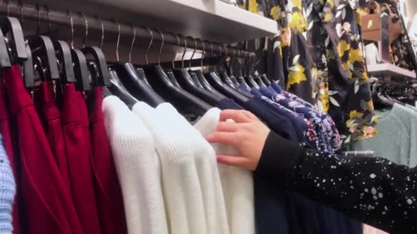 若い女性やティーンエイジャーの手は 衣料品店にかかっているものから選択して 服を分類しています — ストック動画