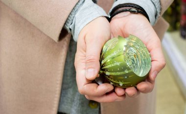 Kırık cam, yeşil Noel ağacı topunun kadın ellerinde yakın plan çekimi..