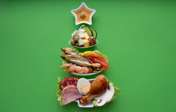 Tabak, içinde protein yiyecekleri olan bir Noel ağacı şeklinde - et, balık, peynir, fındık vb. Yeşil arka plan. Keto diyeti tatili için iyi gelir. Boşluğu kopyala.