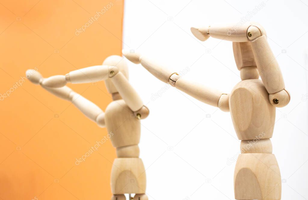 Two wooden human figures on white and orange backgrounds dance and make a dab movement sneezing gesture.