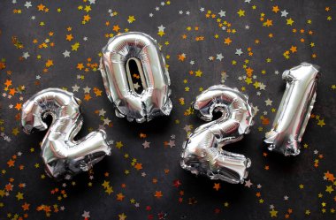 Şişirilebilir sayılara yakın yeni yıl 2021 'de parlak altın, kırmızı ve gümüş yıldızlı siyah arkaplan.