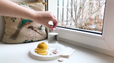 Pencere kenarında limon ve haplarla dolu bir bardak su var. El çözünür, anında ya da çözünür bir tablet bırakır. Su köpürür ve turuncuya döner. C vitamini, beslenme takviyeleri ve antiviral tedavi