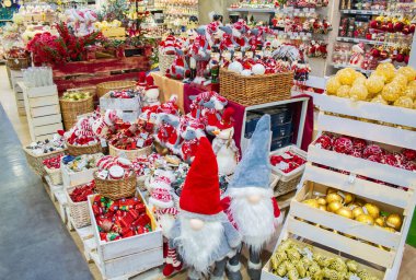 Mağazada Noel oyuncakları ve süslemeler satılıyor: sepetteki kırmızı ve altın toplar, fındıkkıranlar ve fareler, cüce heykelcikler, arabalar, davullar, şeker kamışları, böğürtlenli dallar.