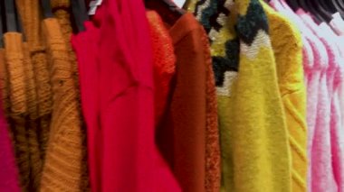 Çok sayıda renkli kadın kazak ve kazak askıları üzerinde kamera hareketi. Alışveriş konsepti, Kara Cuma