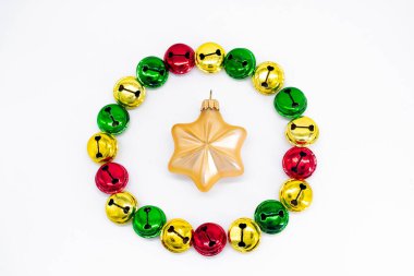 Kırmızı ve yeşil olarak Noel çanları çalıyor. Ortasında altın yıldız noel süslemesi olan daire şeklinde. Noel konsepti. Tatil arkaplanı.