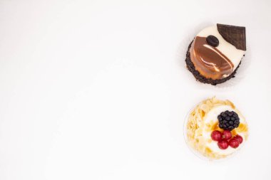 Beyaz arka planda iki kek: badem yapraklı peynirli kek, kırmızı frenk üzümü ve böğürtlen ve bir parça çikolatalı kahve keki ve parlak parlak beyaz ve kahverengi jöleli. Boşluğu kopyala.