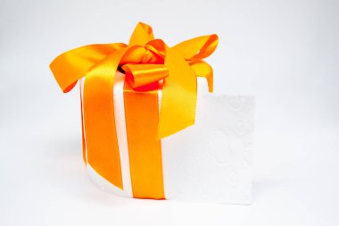 Beyaz delikli yumuşak tuvalet kağıdı, parlak turuncu bir fiyonk, hediye gibi. Beyaz arkaplan.