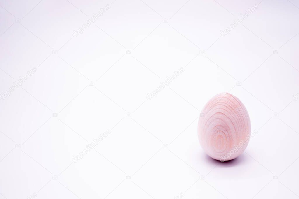 One unpainted hand-made wooden egg on a white background. Copy space.