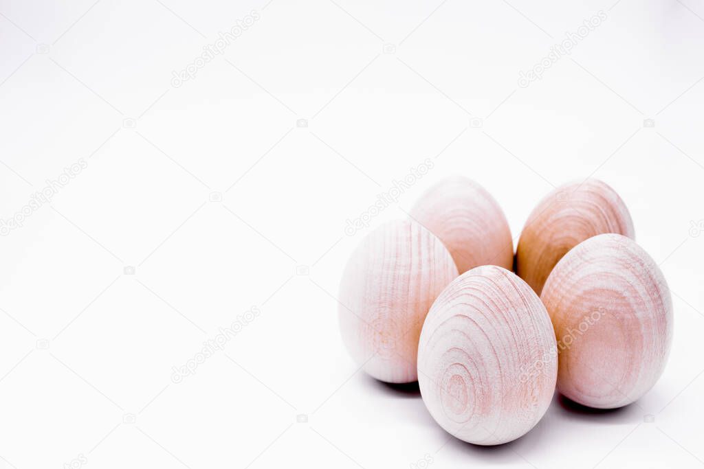 Five hand-made unpainted wooden eggs on a white background.