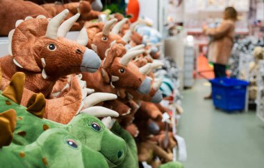 Oyuncak dinozorların raflardaki yakın çekimleri. Arka planda bulanık müşteriler.