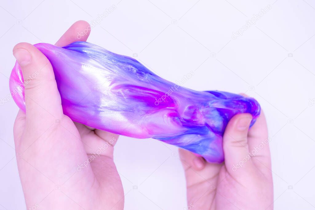 lose up of game with two-color blue and pink slime in someone hands on a white background. The mucus is crushed, stretched, torn and squeezed by hands.