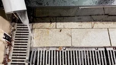 Moskova, Rusya, Mayıs 2021: Yağmur sırasında yeni bir parlak fırtına drenajı. Su kanalizasyon borusundan dökülüyor ve ızgaradan yere dökülüyor.