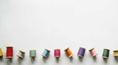 Eski moda ahşap makaralarda, beyaz arka planda, yazı için yeri olan bir sürü renkli iplik. İpliklerden biri boştu..