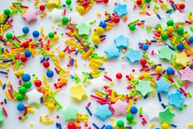 Çörekler ve diğer hamur işleri için serpiştirilmiş şeker şekerlerinin yıldız, sopa ve toplar şeklinde rengarenk arka planı. Parlak kırmızı, pembe ve yeşil, mavi ve sarı.