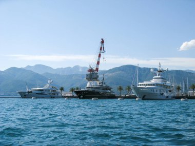 Karadağ, Haziran 2011: Karadağ kıyısı açıklarındaki özel yatların demirleme yerindeki suya bakın. Park yerinde siyah, beyaz yatlar, limanda bir vinç ve denizde büyük bir şamandıra var..