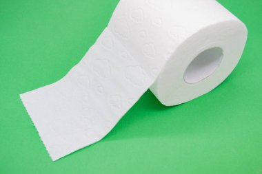 Yeşil arka planı delinmiş beyaz tuvalet kağıdı rulosu..