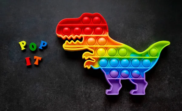 Toy Pop Dinosaurier Regenbogenfarben Auf Schwarzem Hintergrund Mit Bunten Buchstaben — Stockfoto