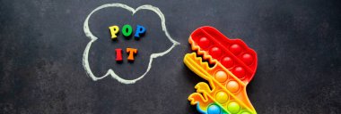 Üzerinde çok renkli harflerle siyah bir arkaplan üzerinde dinazor oyuncağı gökkuşağı renkleri olan pankart - Konuşma baloncuğuna yerleştir.