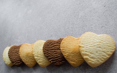 Kalp şeklinde çok renkli kurabiyeler: vanilya, limon, çikolata. Gri arkaplan, alanı kopyala.