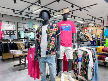 Moskova, Rusya, Haziran 2021: Erkek Giyim Bölümü. İki erkek manken tişört, şort, mağazanın ortasında Hawaii gömleği. Rastgele giysili raflar etrafta. Yaz indirimi.