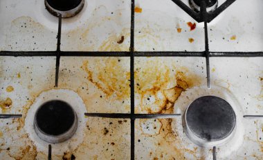 Sarı çizgileri ve yağlı lekeleri olan çok kirli beyaz bir gaz sobasının üst görüntüsü..