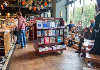 St. Petersburg, Rusya, Ağustos 2021: Çevrimiçi çalışmalar için çalışma alanları olan bir kitapçı, uzaktan çalışma. Ziyaretçiler kitap okur, yer, içer ve konuşurlar. Akıllı telefonu olan küçük bir çocuk..