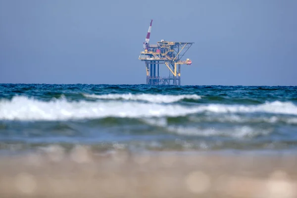 Ameland,Netherlands April 20,2021-NAM, Oil rig, offshore platform with beach, sand and surf. Natural gas extraction in the Wadden-North Sea Region, Wadden Island, nature conservation area:Het Oerd.