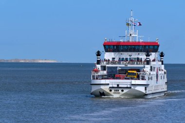 Waddensea, Hollanda-26 Nisan 2021: Wadden Denizi 'nden Batı Frizya adası Ameland' dan Holwerd, Friesland 'a yolcu taşıyan feribot. Arka planda ada schiyermonnikoog 'u