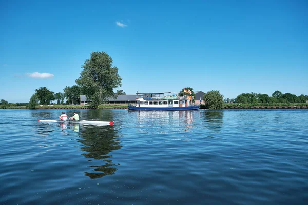 Amersfoort, Hoogland, Hollandia 2021. június 13., Bicikli csónak, komp semland az Eem folyón kenuval és gát és kék égbolttal a háttérben. Hajókirándulás az Eemvallei és t Gooi között — Stock Fotó