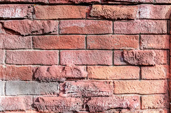 Stone wall patterned bricks, carved uneven imitation of a red brick wall, plaster. Texture. — Stock Photo, Image