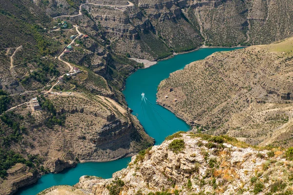 Łódź płynie wzdłuż niebiesko-zielonej rzeki Sulak w pogodny słoneczny dzień. Kanion Sulak jest jednym z najgłębszych kanionów na świecie i najgłębszym w Europie. Dagestan, Rosja. Zdjęcia Stockowe bez tantiem