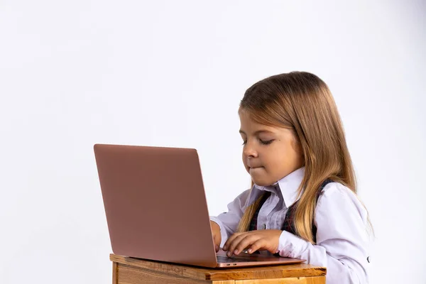 Educación en línea para niños. Una colegiala enseña el plan de estudios de la escuela usando una computadora portátil. Foto en el fondo blanco —  Fotos de Stock