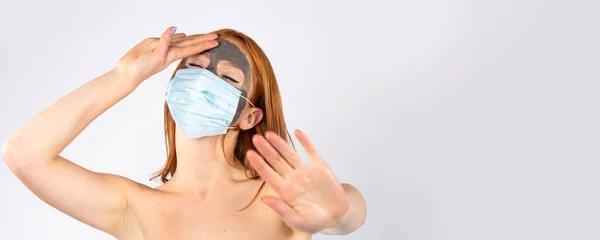Banner, format lung. O fată frumoasă obosită, în salon, cu o mască cosmetică pe față și alta pentru o pandemie, care arată virusul stop. Frumusețe, spa, sănătate și concept covid 19 — Fotografie, imagine de stoc
