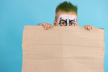 Hevesi kırılmış çocuk elinde boş protesto kartonuyla mavi arka planda izole edilmiş boş bir alan tutuyor. Sosyal sorunlar, insanlar ve Cadılar Bayramı konsepti. Cadılar Bayramı 'nı kutluyoruz. Yüksek kalite fotoğraf