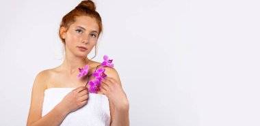 Banner, uzun format. Güzellik portresi. Temiz ve nemli derisi olan kızıl saçlı bir kadın elinde bir orkide çiçeği tutuyor. Cilt bakımı ve güzellik anlayışı. Yüksek kalite fotoğraf