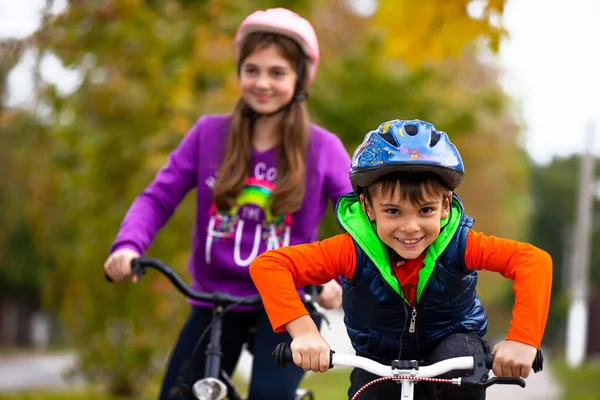  Aile tatili. Erkek ve kız kardeş parkta. Oğlan bisiklette yalnız. Arka planda sonbaharın arka planında bisikletleri olan kız. Yüksek kalite fotoğraf