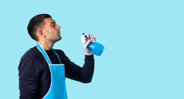 Banner, uzun format. Lastik eldivenli ve elinde sprey tabancası olan bir adam havaya sıkar. Mavi arkaplanda büyük boş yan boşluğu olan bir fotoğraf. Yüksek kalite fotoğraf