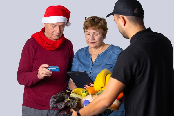 Η οικογένεια πληρώνει με πιστωτική κάρτα, για τα χριστουγεννιάτικα ψώνια που παραγγέλνονται με κούριερ. Ανώτερος έννοια online και Χριστούγεννα έννοια. Φωτογραφία σε λευκό φόντο — Φωτογραφία Αρχείου